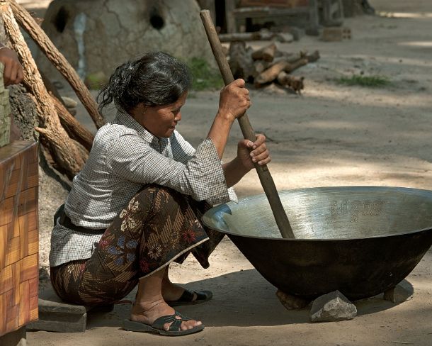 sm_khN1199 Khmer woman stirring palm sugar syrop in a big traditional metal pan Siem Reap, Cambodia