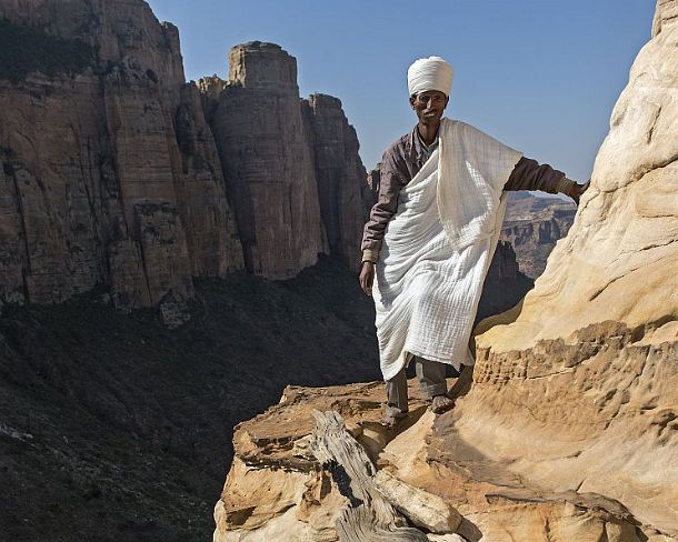 sm1gva_ET_cx2518_g Coptic priest standing at the entry to the rock-hewn church Abuna Yemata situated high up at a steep rock pinnacle, Gheralta, Tigray, Ethiopia