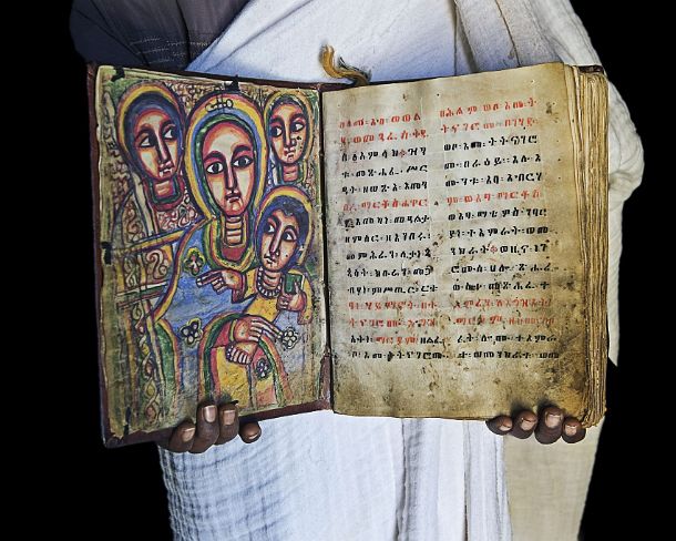 smgva_ET_x2484_g Orthodox priest of rock-hewn church Abuna Yemata showing a book of the miracles of Maria hand-written in Ge'ez language on parchment, Gheralta, Tigray, Ethiopia