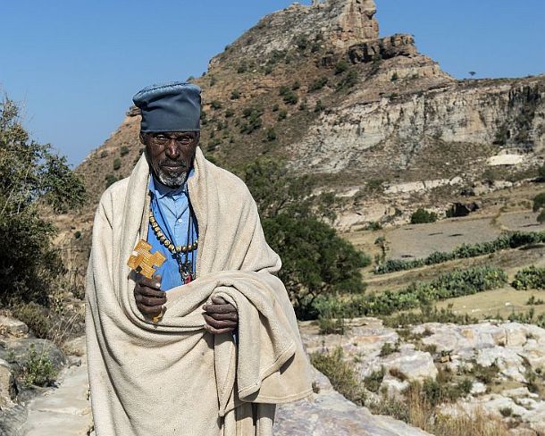 sm1gva_ET_x2050_g Orthodox Priest at a rock ledge leading to rock-hewn church Daniel Korkor, Gheralta mountains, Tigray, Ethiopia