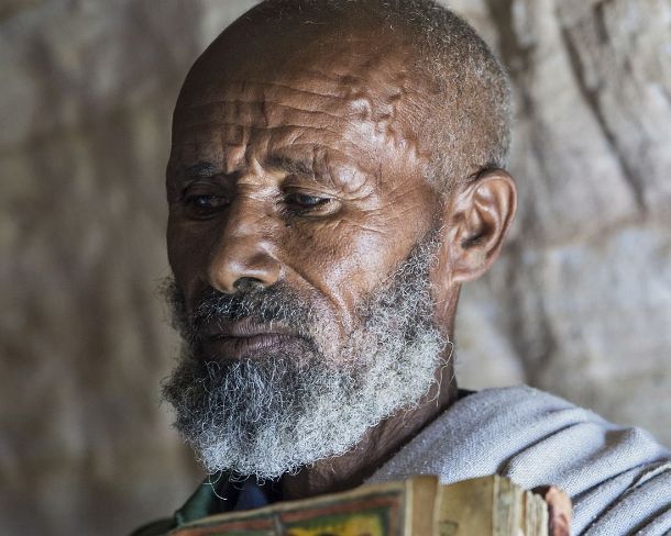 smgva_ET_1654_g Coptic priest of rock-hewn church Mikael Mellehayzengi showing a book of the miracles of Maria illustrated by hand on parchment, Gheralta, Tigray, Ethiopia