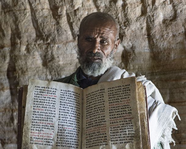 smgva_ET_1657_g Coptic priest of rock-hewn church Mikael Mellehayzengi showing a book of the miracles of Maria written by hand on parchment in Ge'ez language, Gheralta, Tigray,...