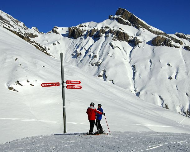 smRM_CH_02310_u Two sikiers standing at a directional sign in front of an impressive mountain range of the skiing area Ovronnaz, Ovronnaz, Valais, Switzerland